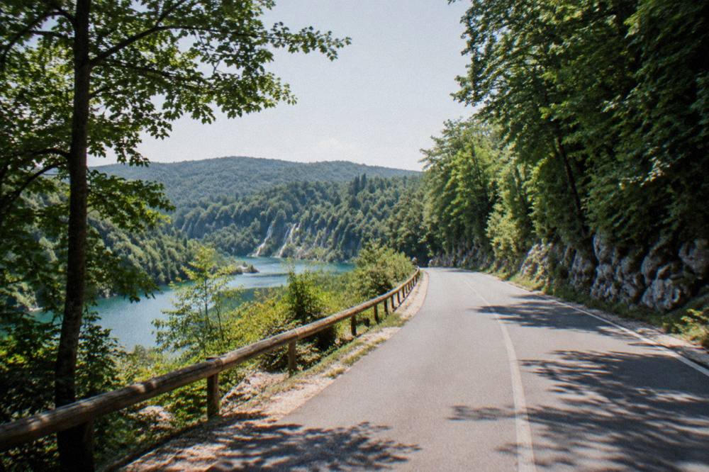 An empty inland road winding through forested hills on the drive to Plitvice