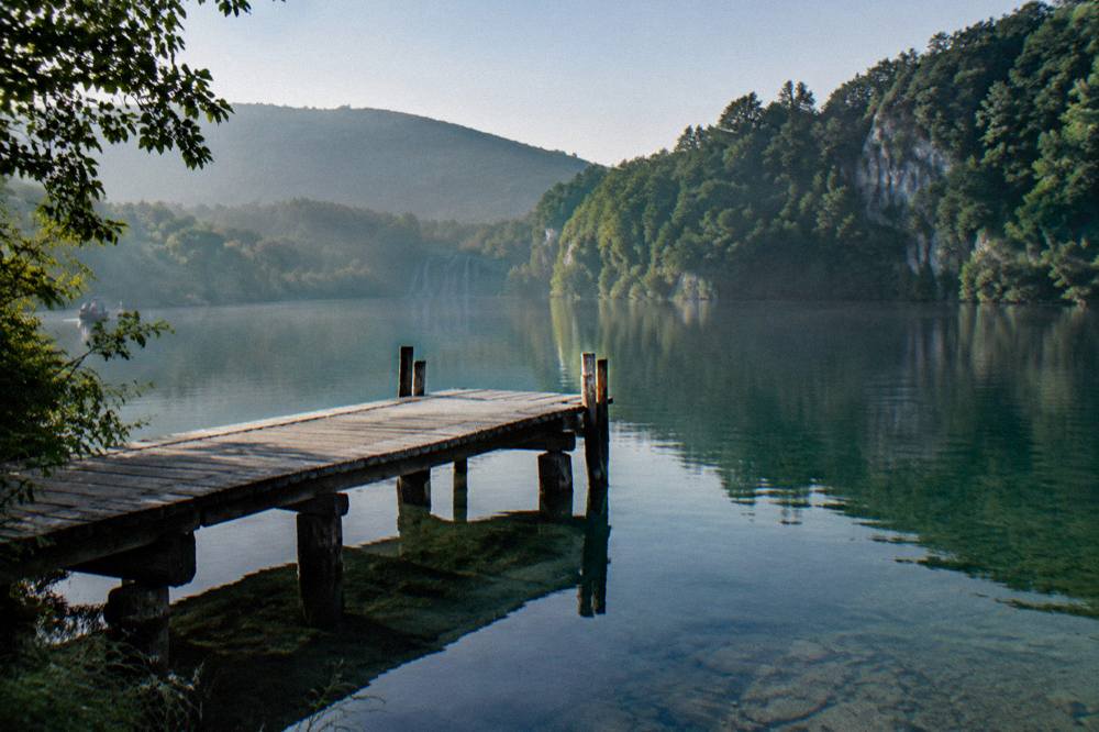 A small wooden pier on a quiet Plitvice lake in early morning light