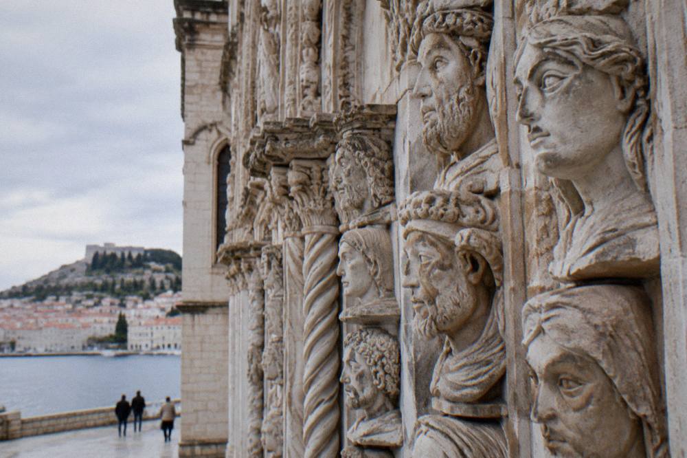 Close view of a stone cathedral facade carved with rows of human faces