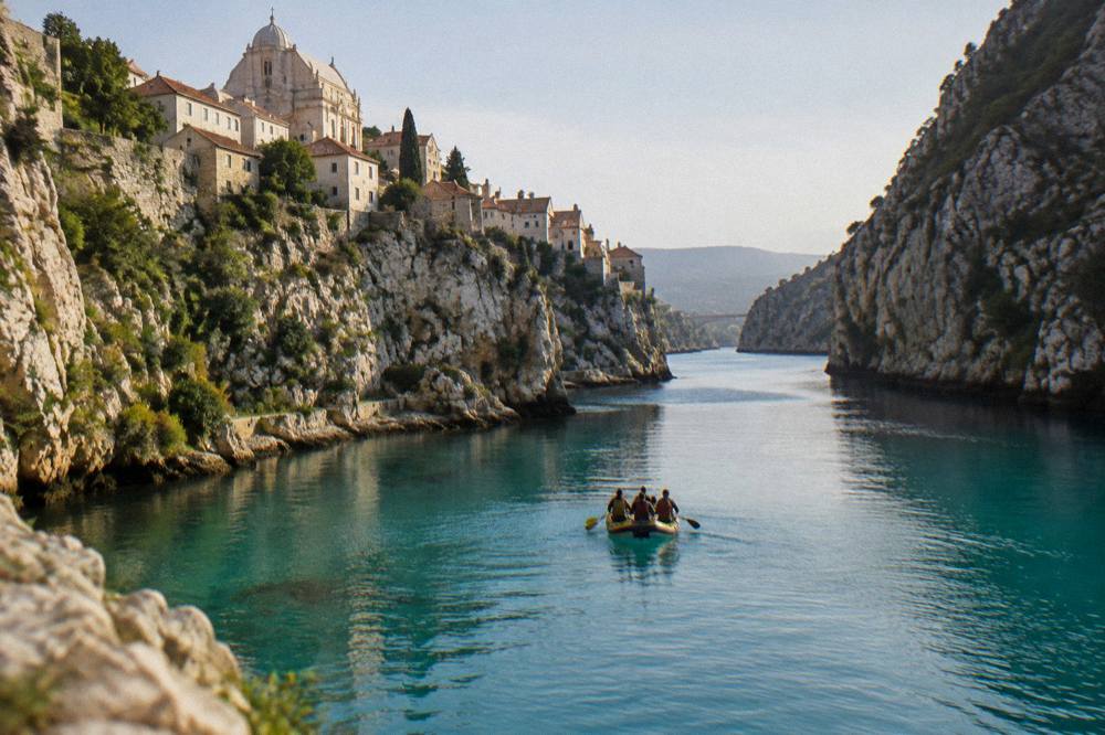 Raft and paddlers on a turquoise river between steep canyon walls