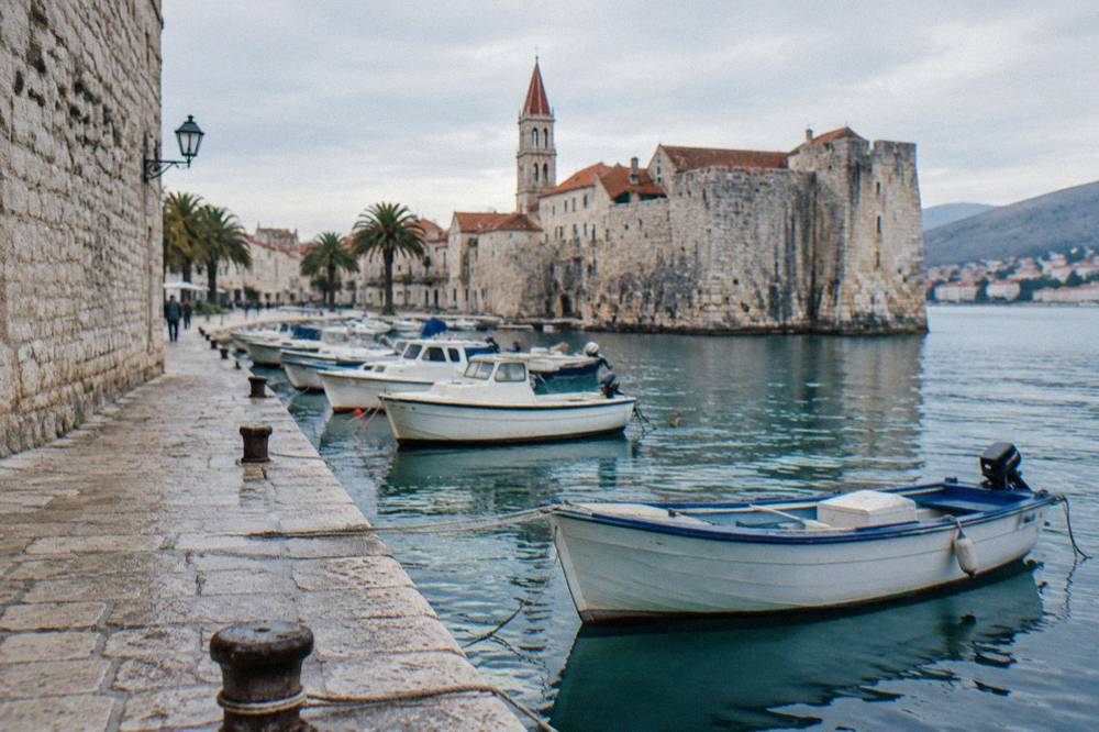 Small boats moored along a stone quay beside old town walls