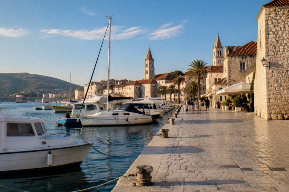 Late afternoon light on a stone waterfront promenade with moored boats