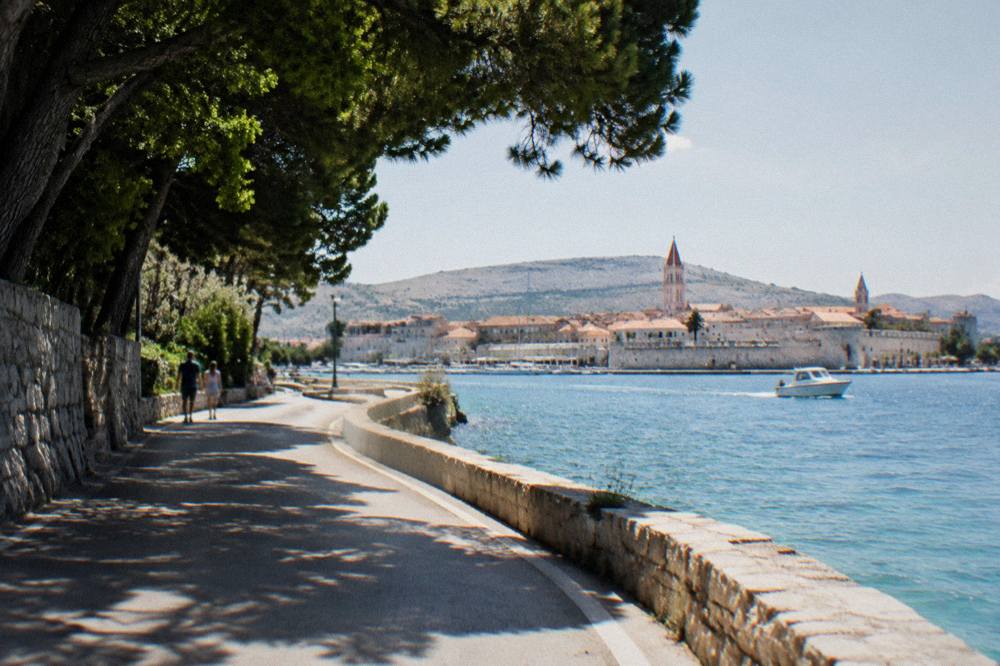 Road winding along the coast with a walled town visible across the water