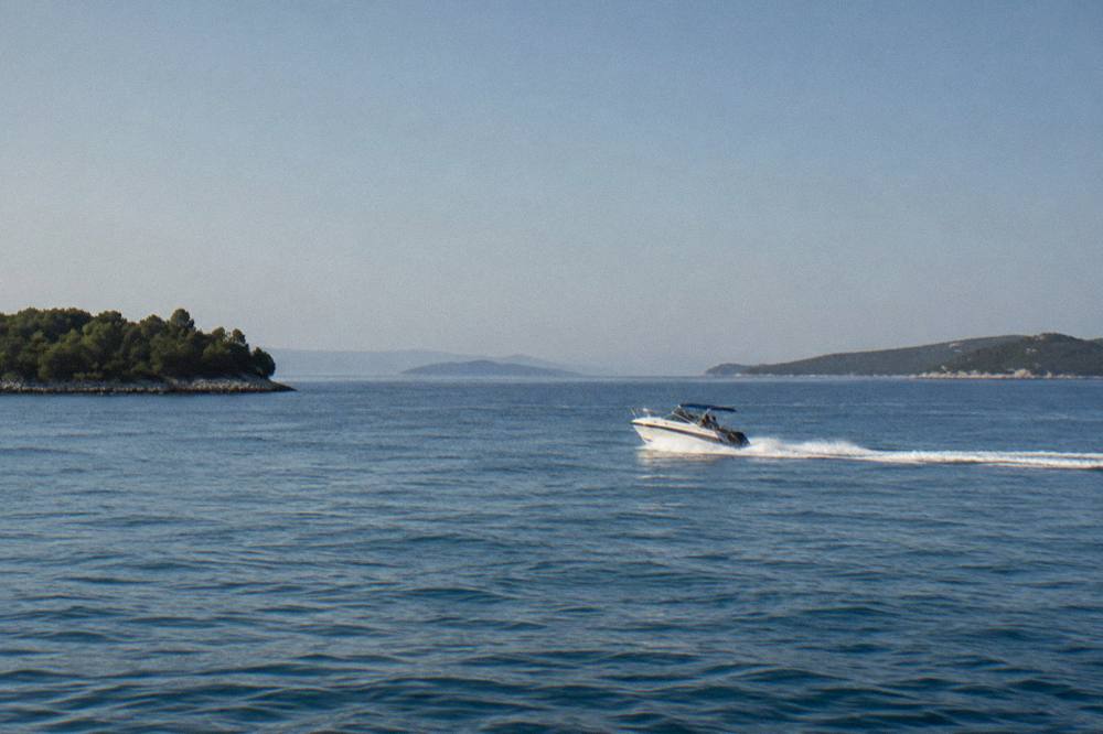 A speedboat crossing open sea between islands near Split under a clear sky