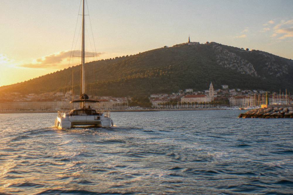 Catamaran pulling away from Split harbour with the Marjan hillside behind