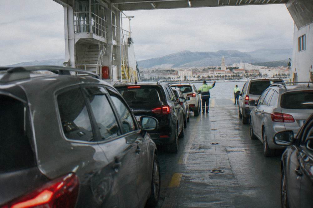 Vehicles lined up on the car deck of a ferry with crew directing traffic