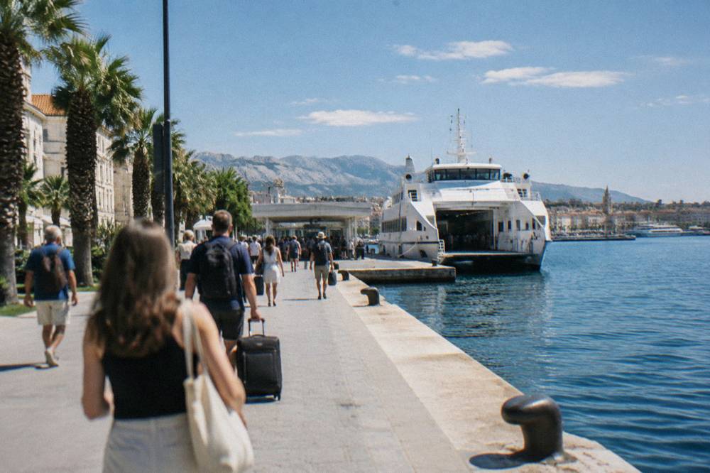 Passengers walking along the Split waterfront promenade towards the ferry terminal
