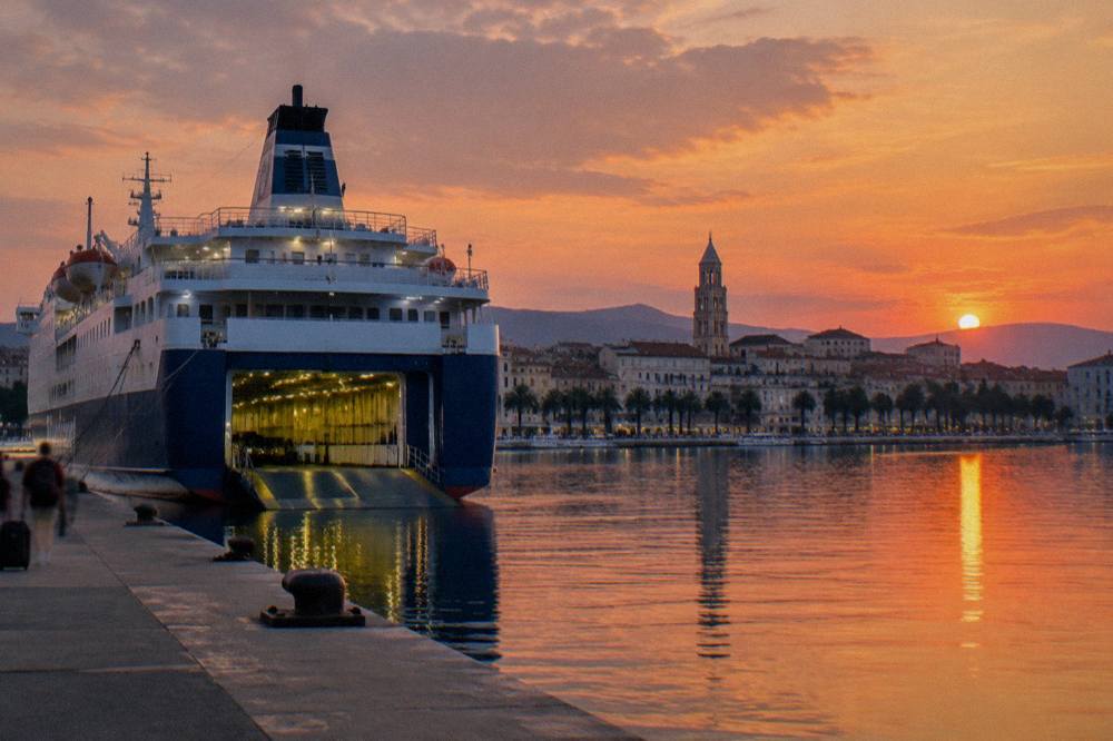 Large overnight ferry at a Split berth at dusk with the old town skyline behind