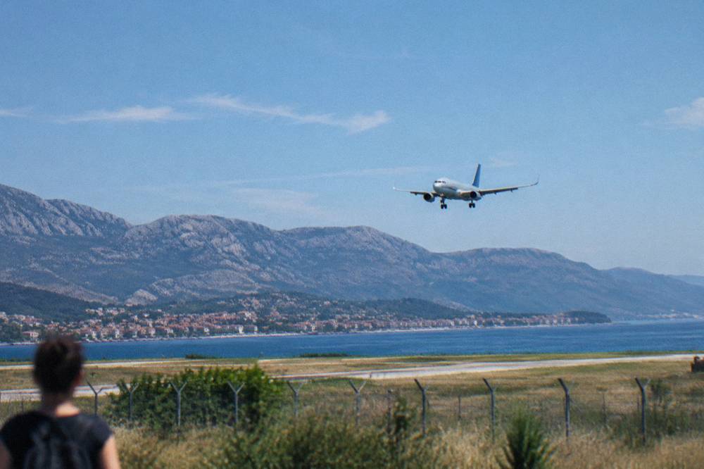 A passenger aircraft on approach over the Kaštela coastline with the Dinaric mountains behind