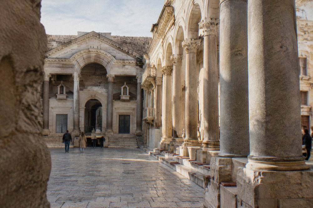 A stone colonnaded courtyard in an old Roman palace with sunlight on the columns