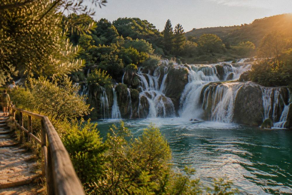 Waterfalls pouring over travertine barriers into a green river in a national park