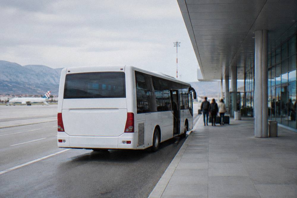 White airport shuttle bus parked at Split Airport terminal kerb