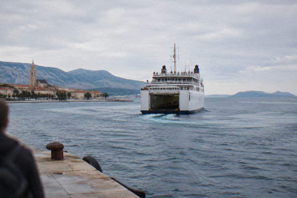 Large car ferry departing Split harbour towards islands on the horizon