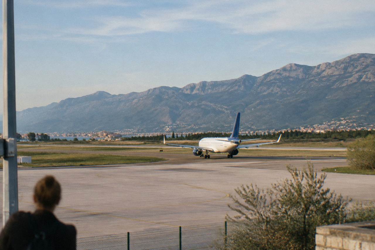 A plane on the runway at Split Airport with hills behind it under a clear sky