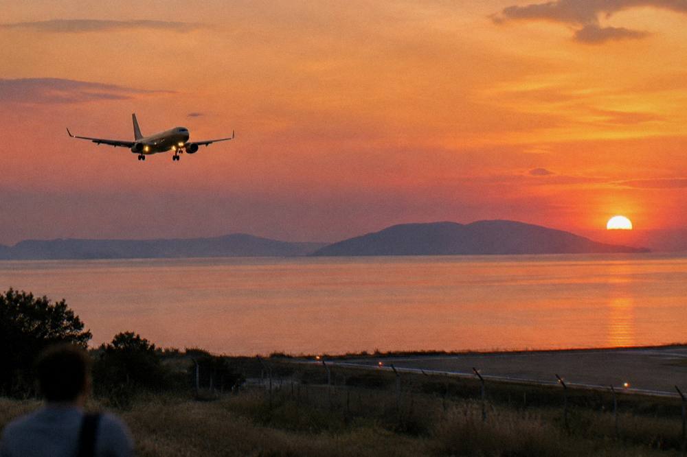Aircraft on approach over the Adriatic coastline near sunset with calm sea below