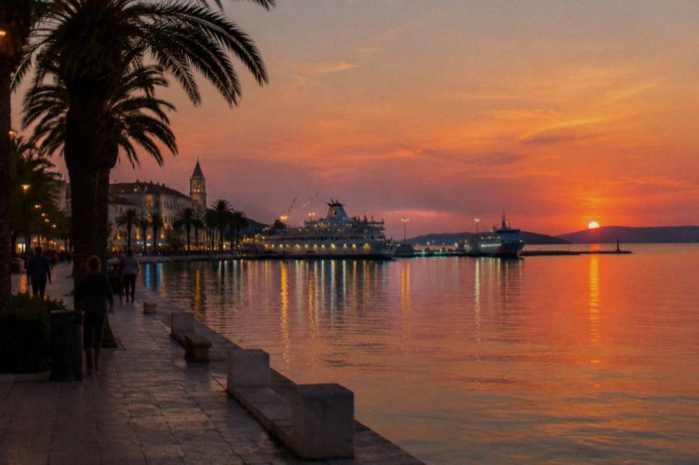 Evening view of the Split Riva promenade with the ferry port lights reflected in the water