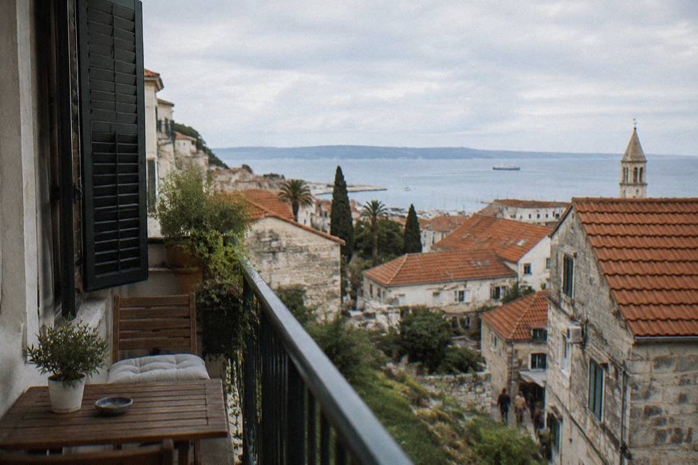 A balcony overlooking terracotta rooftops and the Adriatic sea from a Split apartment