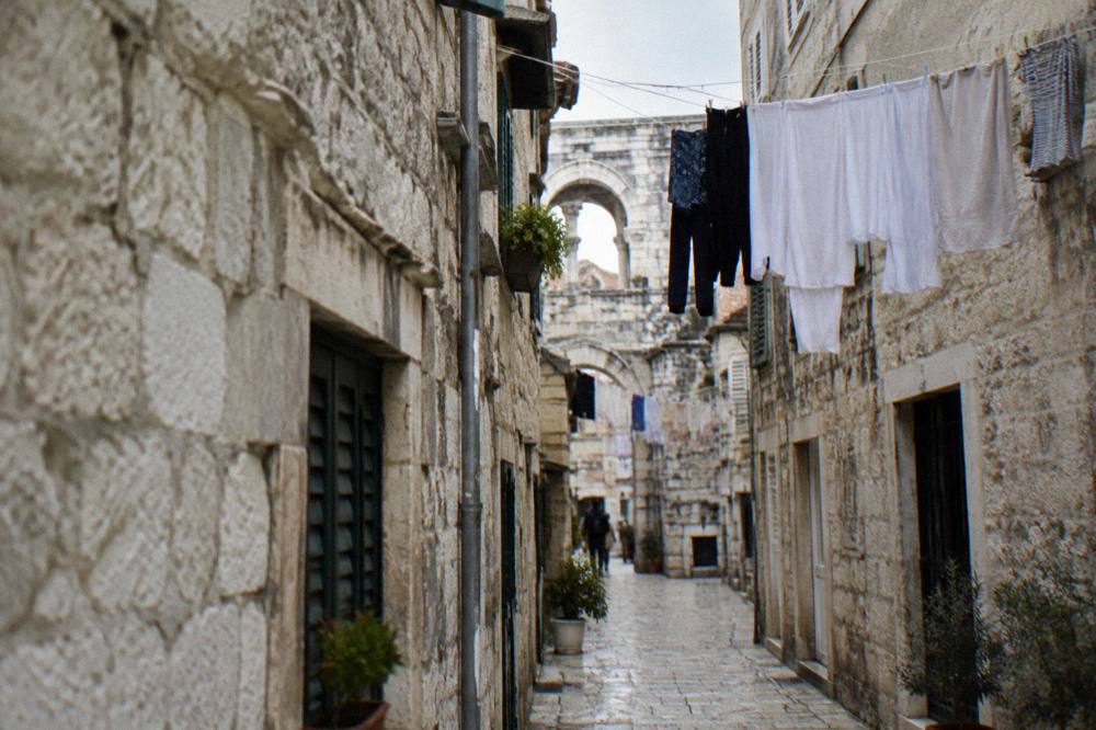 A narrow stone lane inside Diocletian's Palace with laundry hanging between old buildings