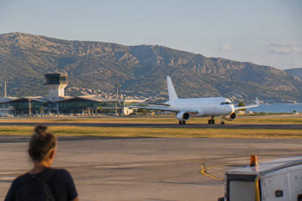 A plane on the runway at Split Airport with hills behind the terminal building