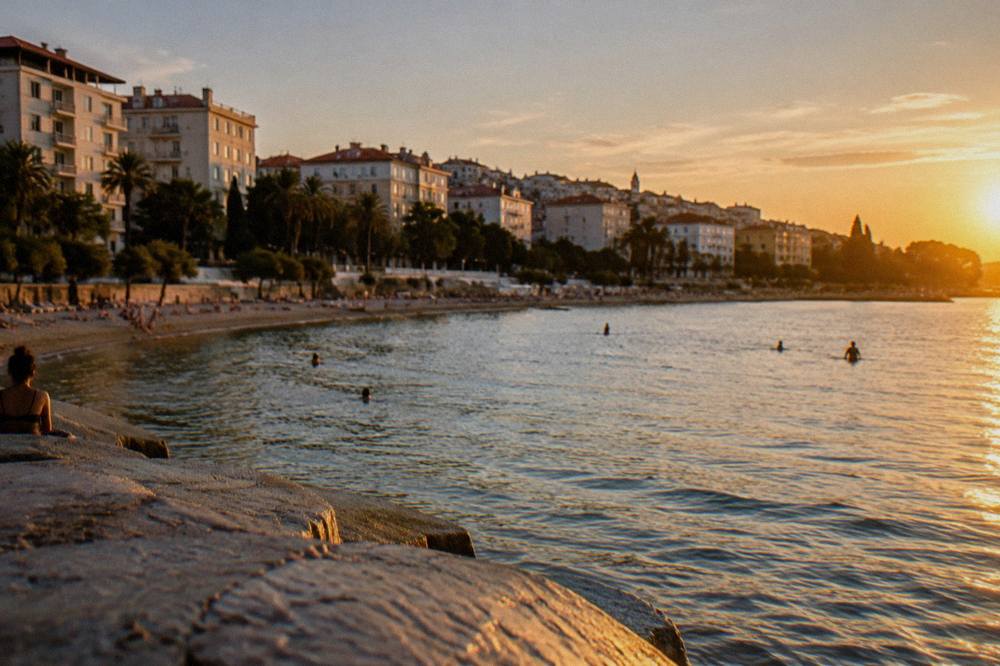 White apartment buildings above a curving city bay with beaches along the shoreline