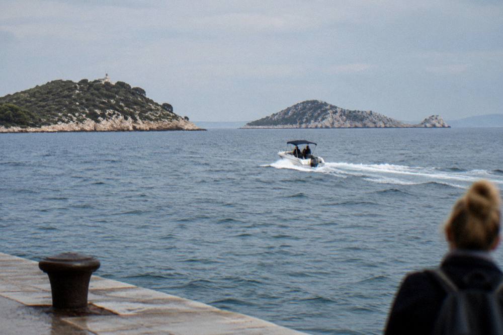 A small speedboat with a canopy cutting across open sea toward rocky islands