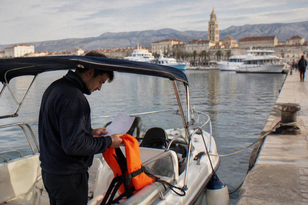 Person in a boat checking paperwork and a life jacket at a harbour pontoon