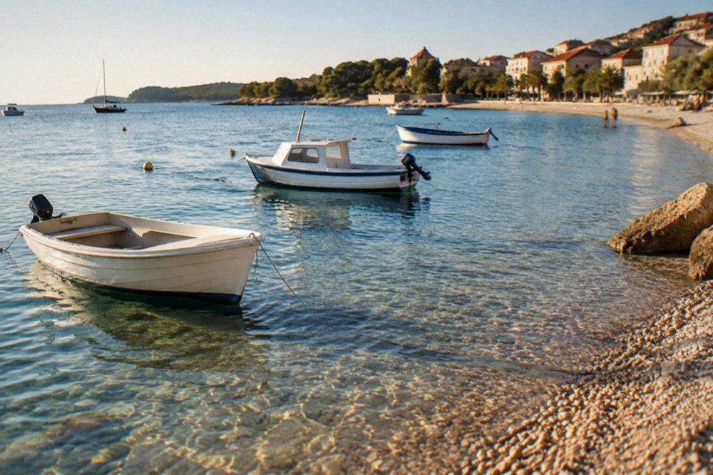 Boats anchored in clear shallow water beside a pebble beach on a Dalmatian island