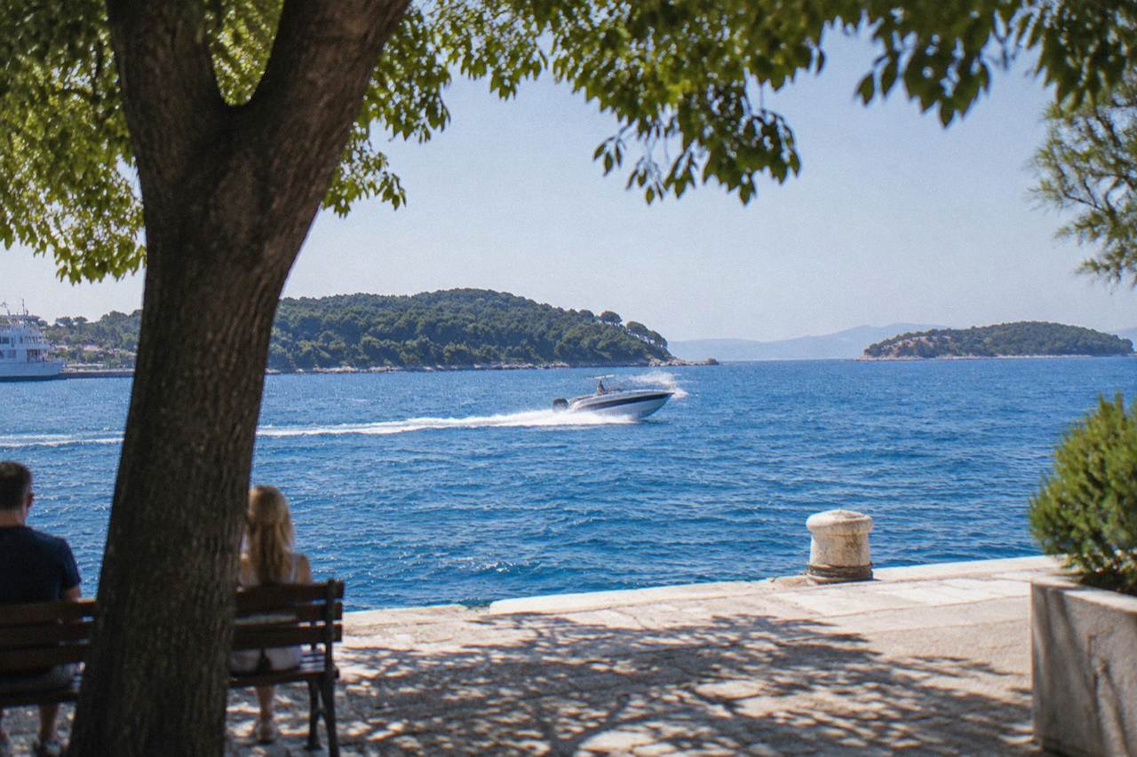 A speedboat cutting across clear blue Adriatic water with wooded Croatian islands on the horizon