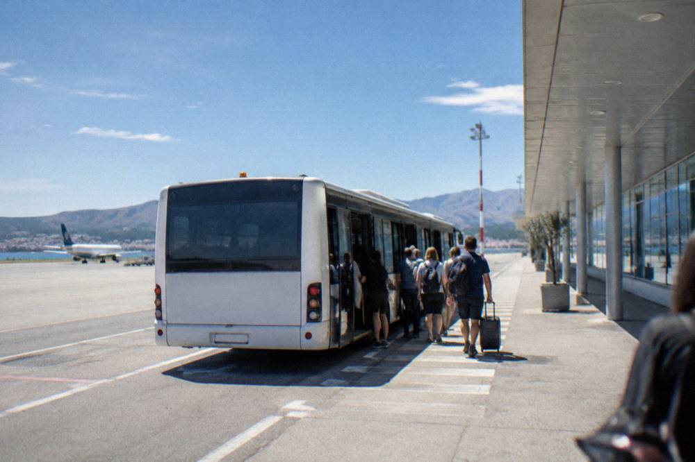 A shuttle bus loading passengers outside Split Airport terminal building