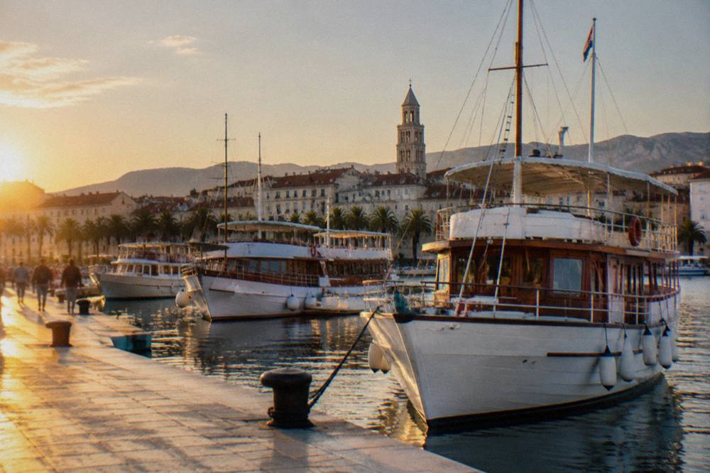 Tour boats moored in a row along the Split waterfront piers in morning light