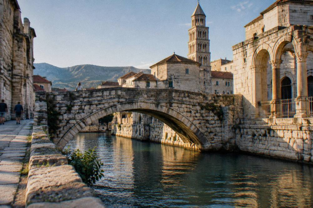 Stone bridge arch spanning a river in a small old town among hills