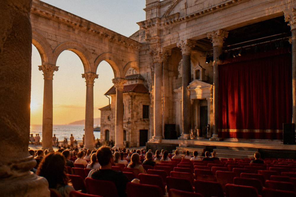 Ornate theatre auditorium interior with red seats and a stage curtain