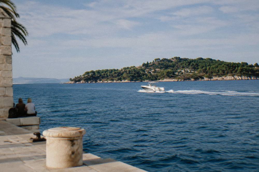 White speedboat crossing open blue sea towards a green island coastline