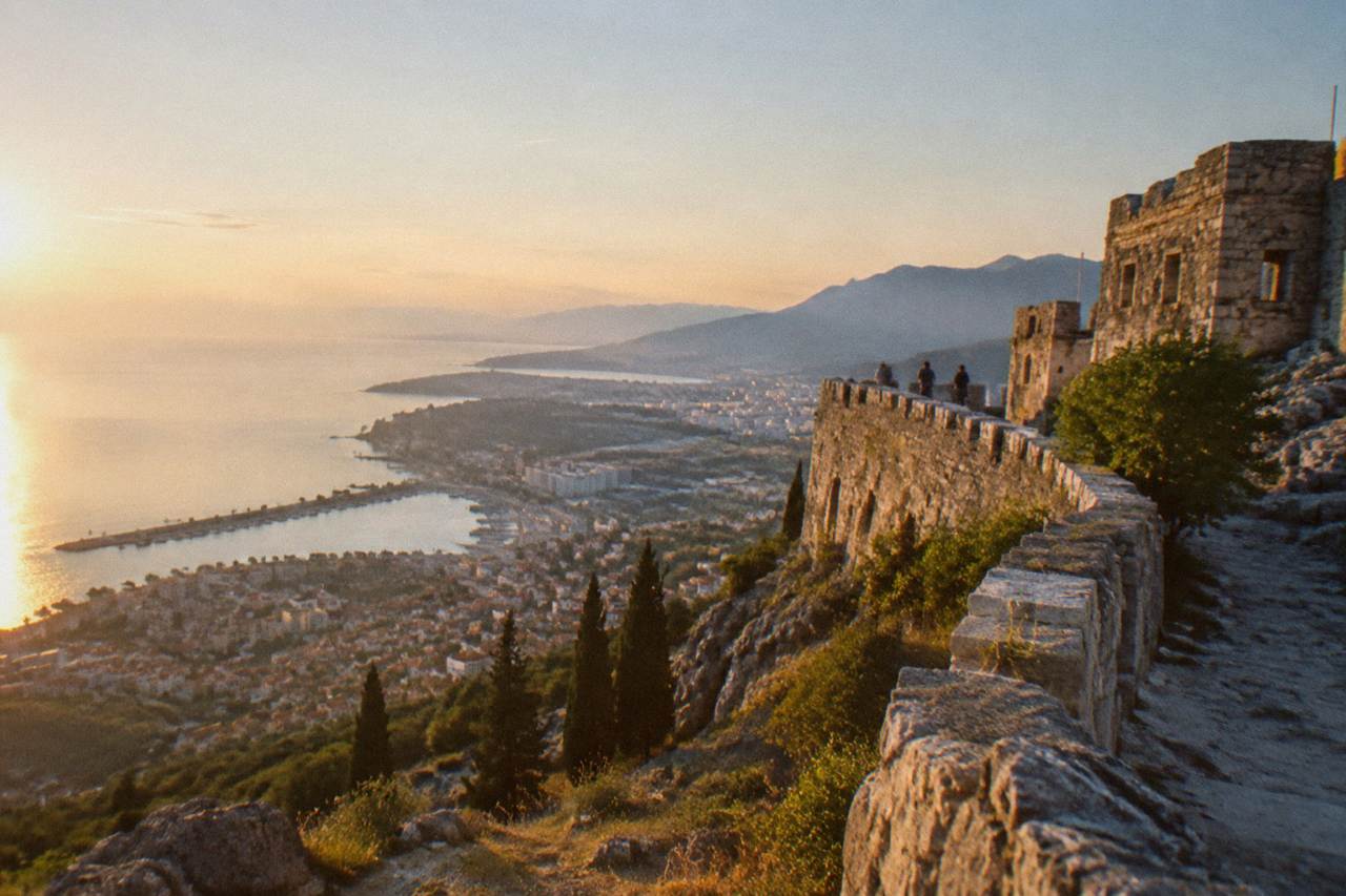 Stone walls of Klis Fortress rising above the Split coastline at golden hour