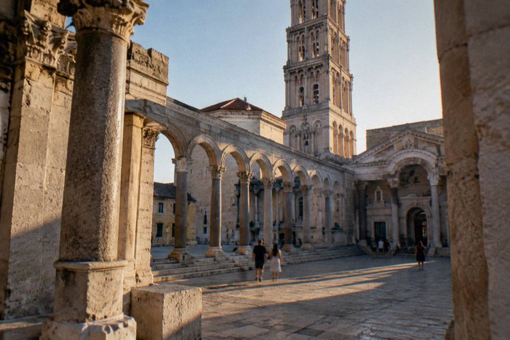 The Peristyle square of Diocletian's Palace with stone columns and the cathedral bell tower behind