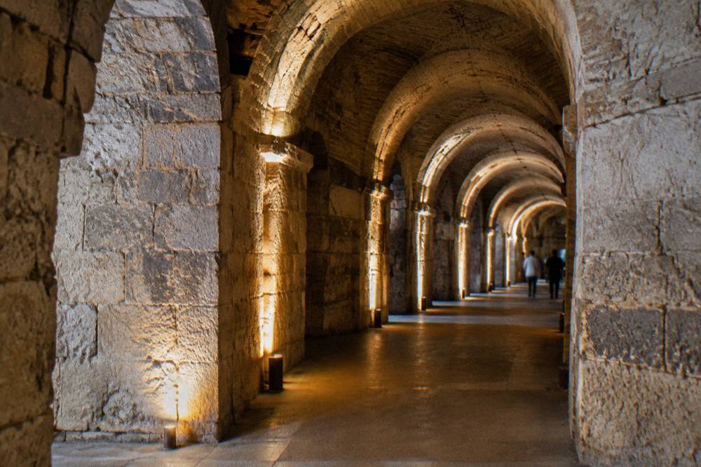 Vaulted stone corridors of the palace substructures lit by warm lamps