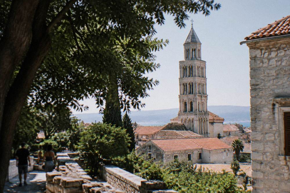 The stone bell tower of the Cathedral of St Domnius rising above red roofs of Split
