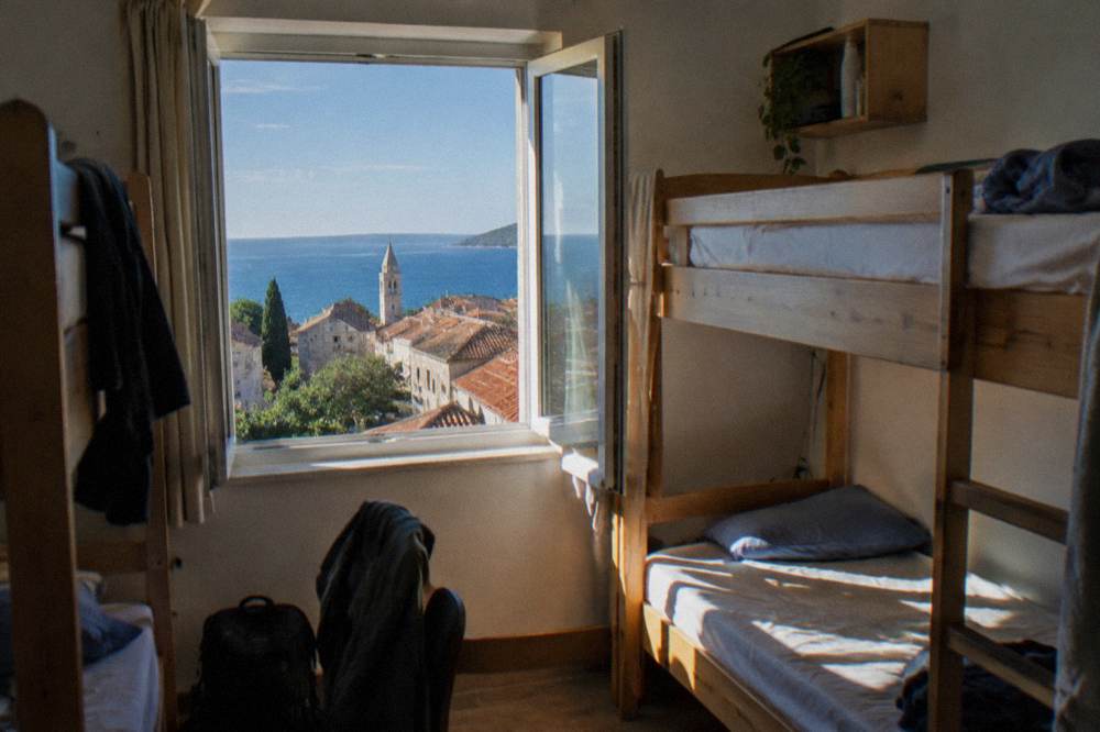 A dormitory room with bunk beds and morning light through a window