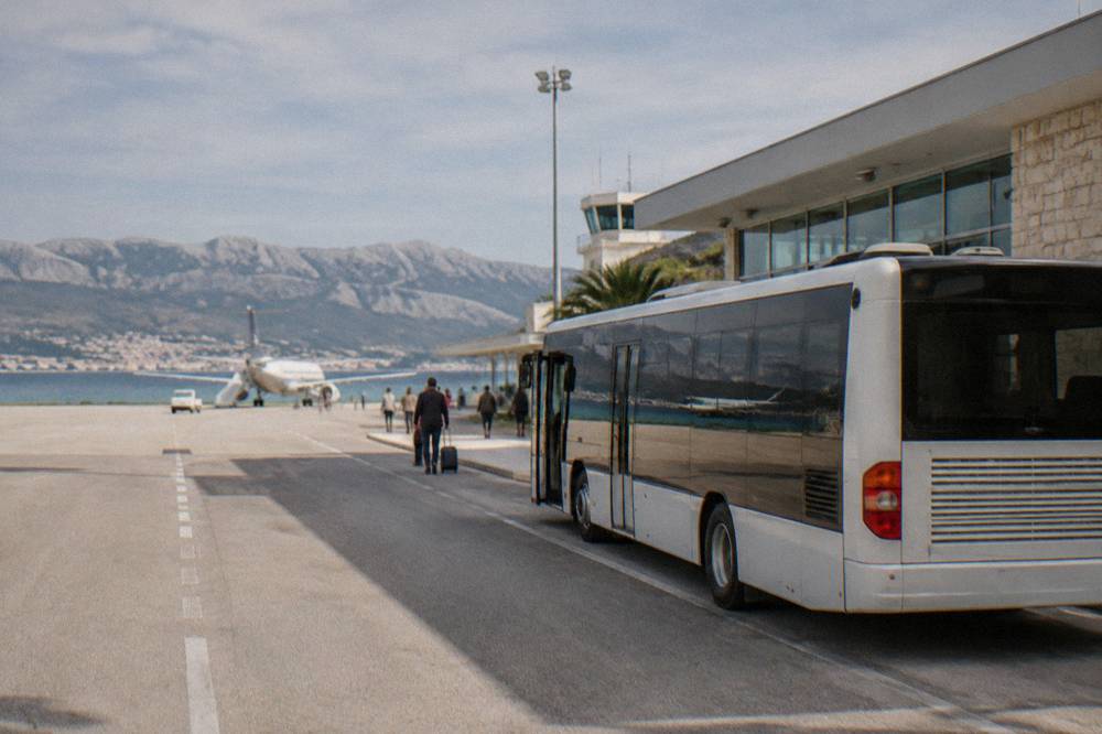 A shuttle bus parked outside a small coastal airport terminal