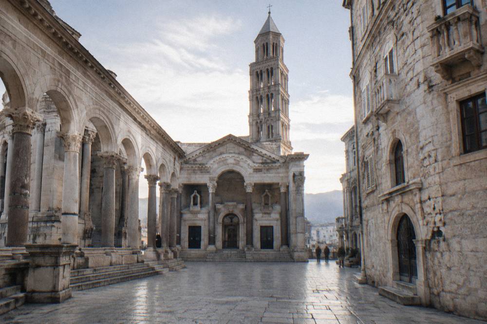 Empty stone square of the Peristyle in Split under a pale winter sky with the cathedral bell tower behind