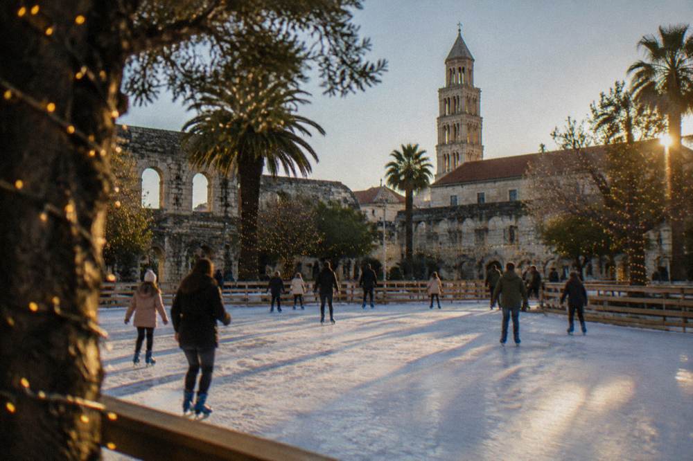 An open-air ice rink in a park in Split with festively lit trees and people skating