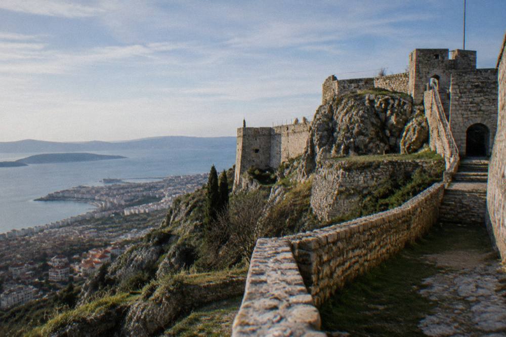 Stone fortifications of Klis Fortress above Split under clear winter light with the coastline below