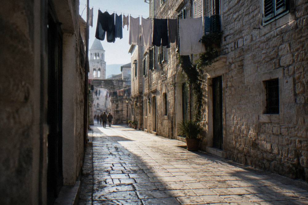 Sunlight on the stone paving of a narrow street in Split old town with laundry lines overhead