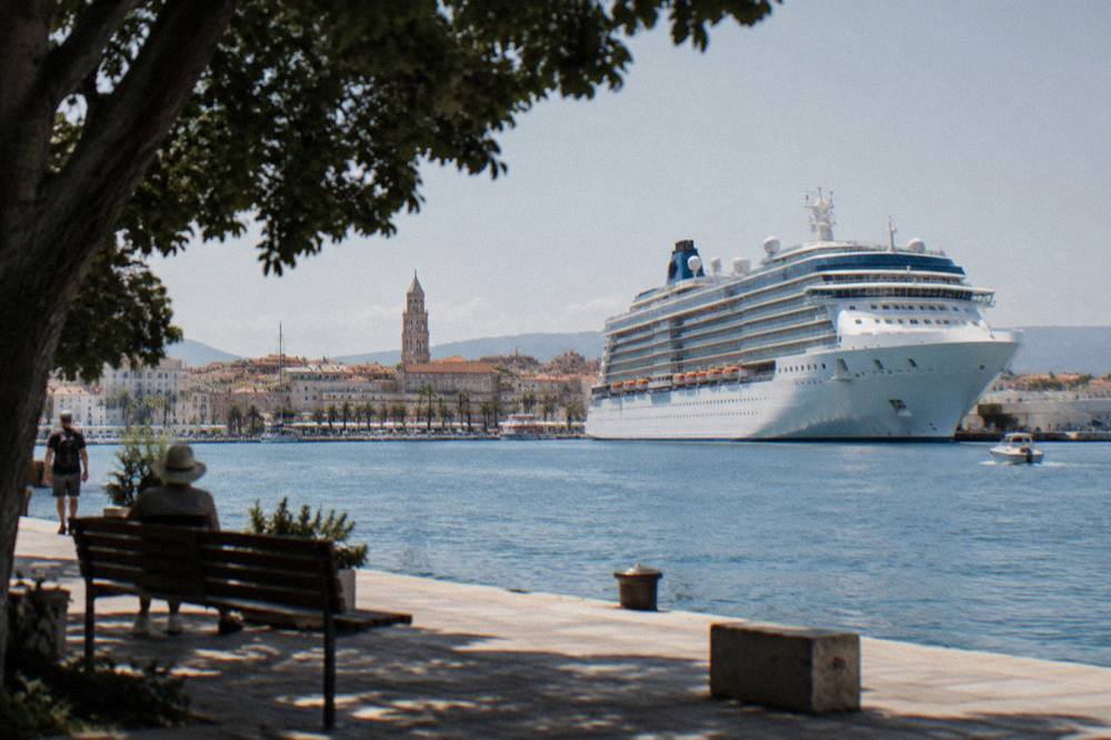 A cruise ship moored at the Split passenger port with the old town rooftops behind it