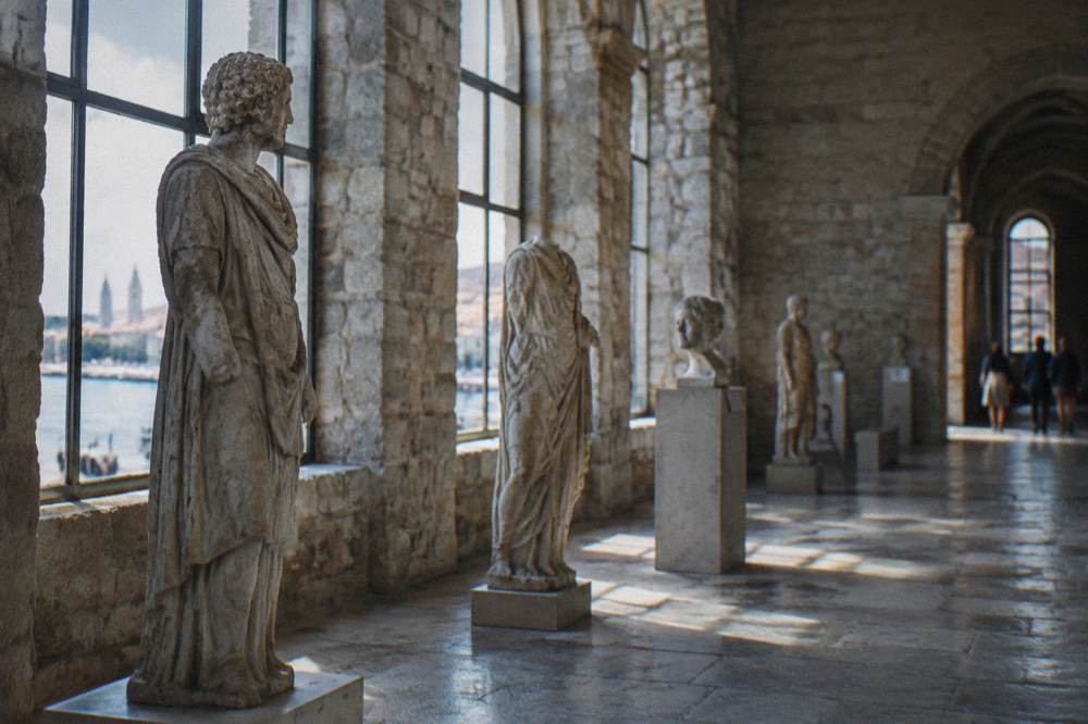 Sculpture gallery interior with stone figures lit by tall windows