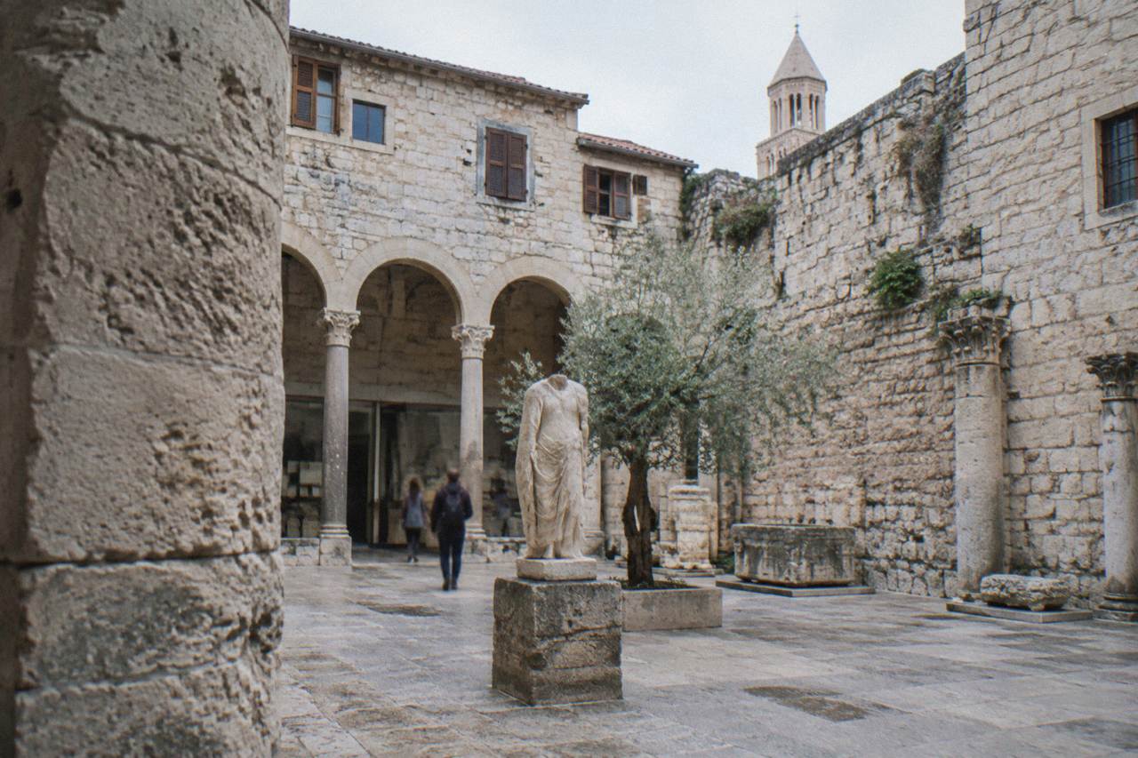 A stone museum courtyard in Split with old palace walls rising above it