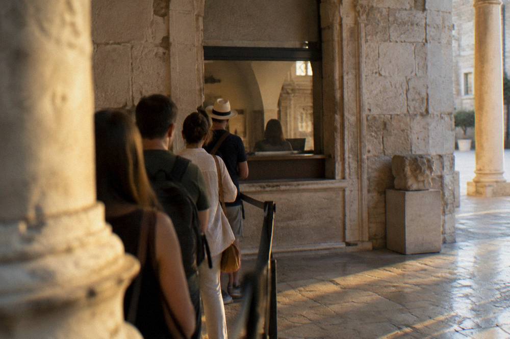 A museum ticket counter in a stone building with a small queue