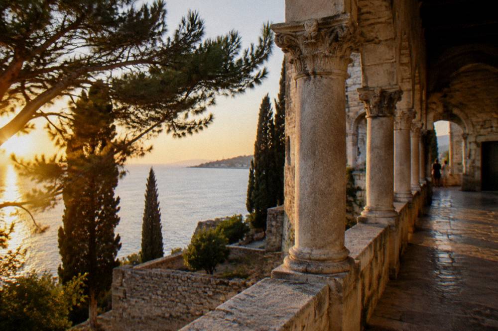 A stone villa gallery above the sea surrounded by pine trees and cypresses