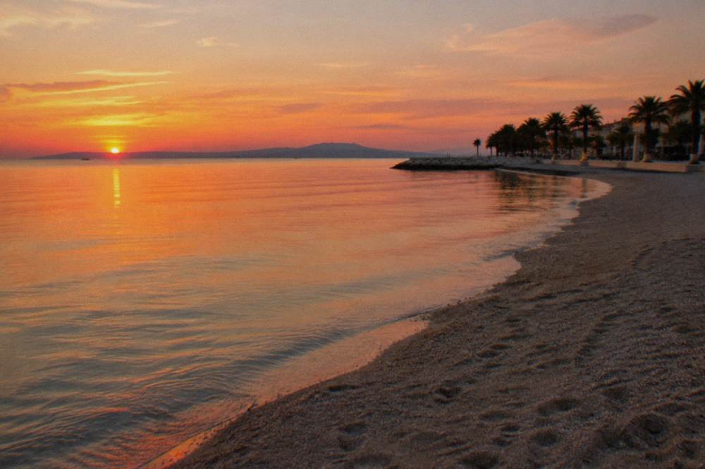 Empty sandy city beach at dusk with warm sky over the Adriatic