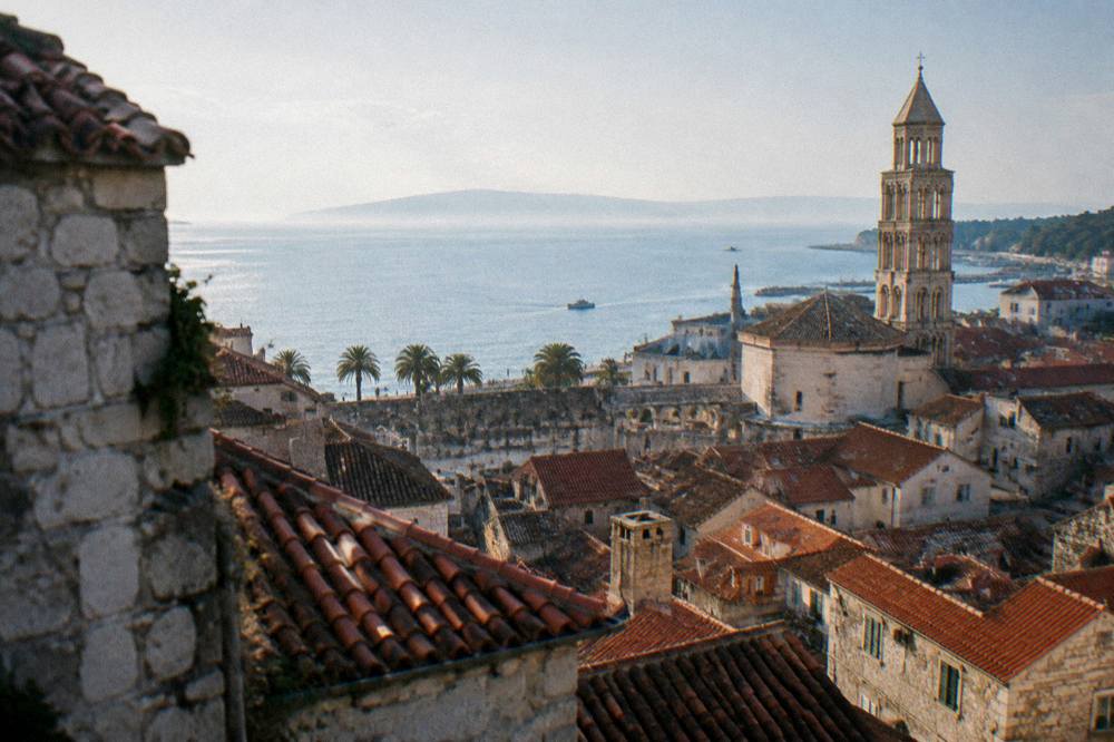 Rooftop view over terracotta roofs of an old town with the sea horizon beyond